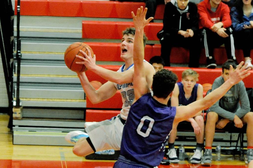 Olympic Trojans guard Tyler Lindal (left) jumps past Sequim Wolves guard Dallin Despain (0) in the second quarter of the Trojans 59-47 win over the Wolves in an Olympic League tiebreaker game on Feb. 8 that sent the Trojans to the district playoffs. Sequim Gazette photo by Conor Dowley
