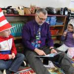 Sequim Middle School teacher Mr. Miko reads to first-graders Derrick Brawner and Hailey Groomes on March 2. Submitted photo