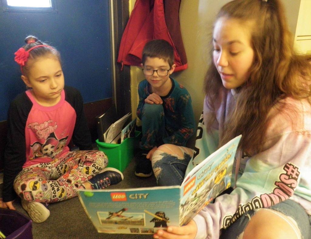 Sequim High School student Jordan Hegtvedt reads to Haller second-graders Avanelle Priest, left, and Micah VanDeWeghe. Haller students dressed in pajamas for Pajama Monday. Photo by Patsene Dashiell