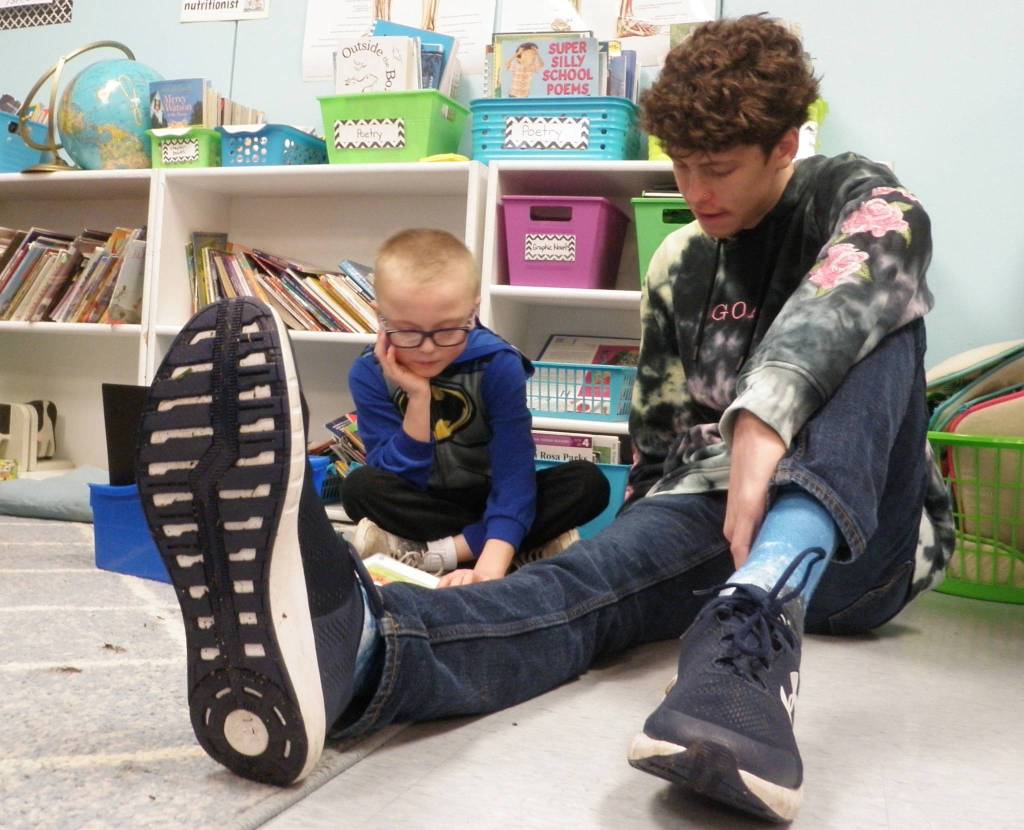 Sequim High School student Adrian Brown hunkers down to read with Helen Haller Elementary second-grader Dalton Wilkinson. Photo by Patsene Dashiell