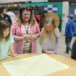 Teacher Linda Jacobson looks on as, from left, students Mackenzye Tate, Kaiya Robinson and Kaeson Robinson check out a math station at the Greywolf Elementary Family Math Night on Feb. 27. Photo by Kalli Wiker