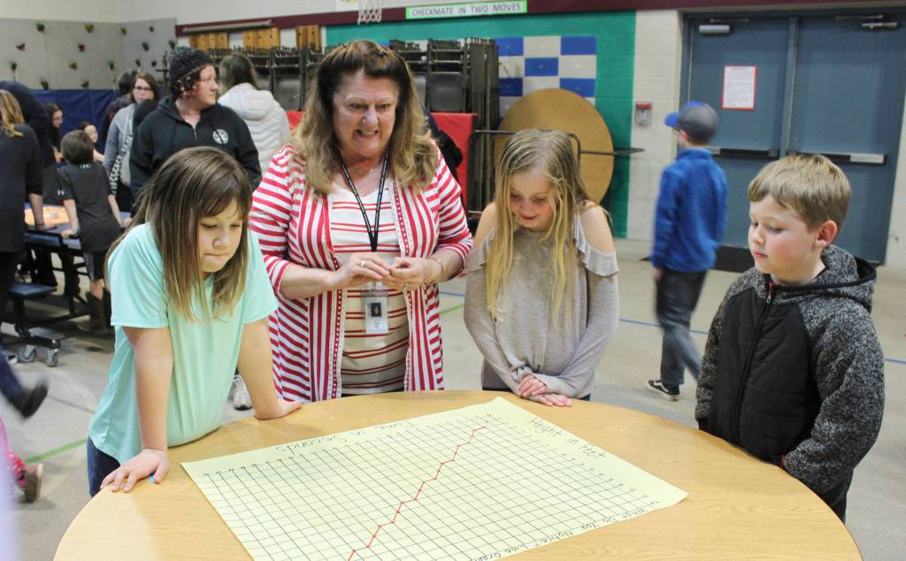Teacher Linda Jacobson looks on as, from left, students Mackenzye Tate, Kaiya Robinson and Kaeson Robinson check out a math station at the Greywolf Elementary Family Math Night on Feb. 27. Photo by Kalli Wiker