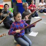 From left, Greywolf third-graders Benjamin Najera, Elise Sundin and Rylie Savage work on their strumming technique in a recent music lesson. Submitted photo