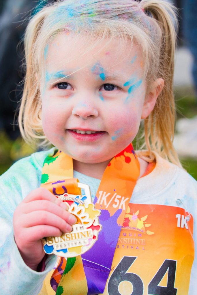 Madelyn Freeman, 3, of Sequim, shows off her Sequim Sunshine Festival Sun Fun Color Run medal after the 1k race. Photo by Heart and Passion Films