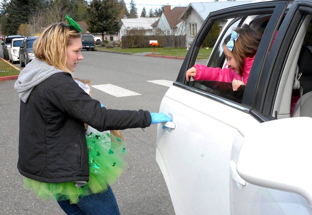 Lucy Wait, a paraeducator at Hamilton School, left, opens the door for student Chloe Sullivan, 7, to receive a free lunch and breakfast at the school on March 17. Youngsters at Hamilton were also given a chance to pick a free book to take home. Photo by Keith Thorpe/Olympic Peninsula News Group