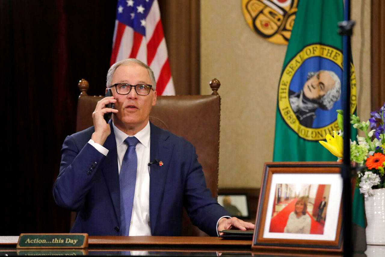 Gov. Jay Inslee takes a phone call just before speaking about additional plans to slow the spread of coronavirus before a televised address from his office Monday, March 23, 2020, in Olympia. Inslee has ordered non-essential businesses to close and the states more than 7 million residents to stay home unless necessary in order to slow the spread of COVID-19. (Elaine Thompson/The Associated Press)