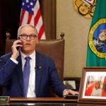 Gov. Jay Inslee takes a phone call just before speaking about additional plans to slow the spread of coronavirus before a televised address from his office Monday, March 23, 2020, in Olympia. Inslee has ordered non-essential businesses to close and the states more than 7 million residents to stay home unless necessary in order to slow the spread of COVID-19. (Elaine Thompson/The Associated Press)