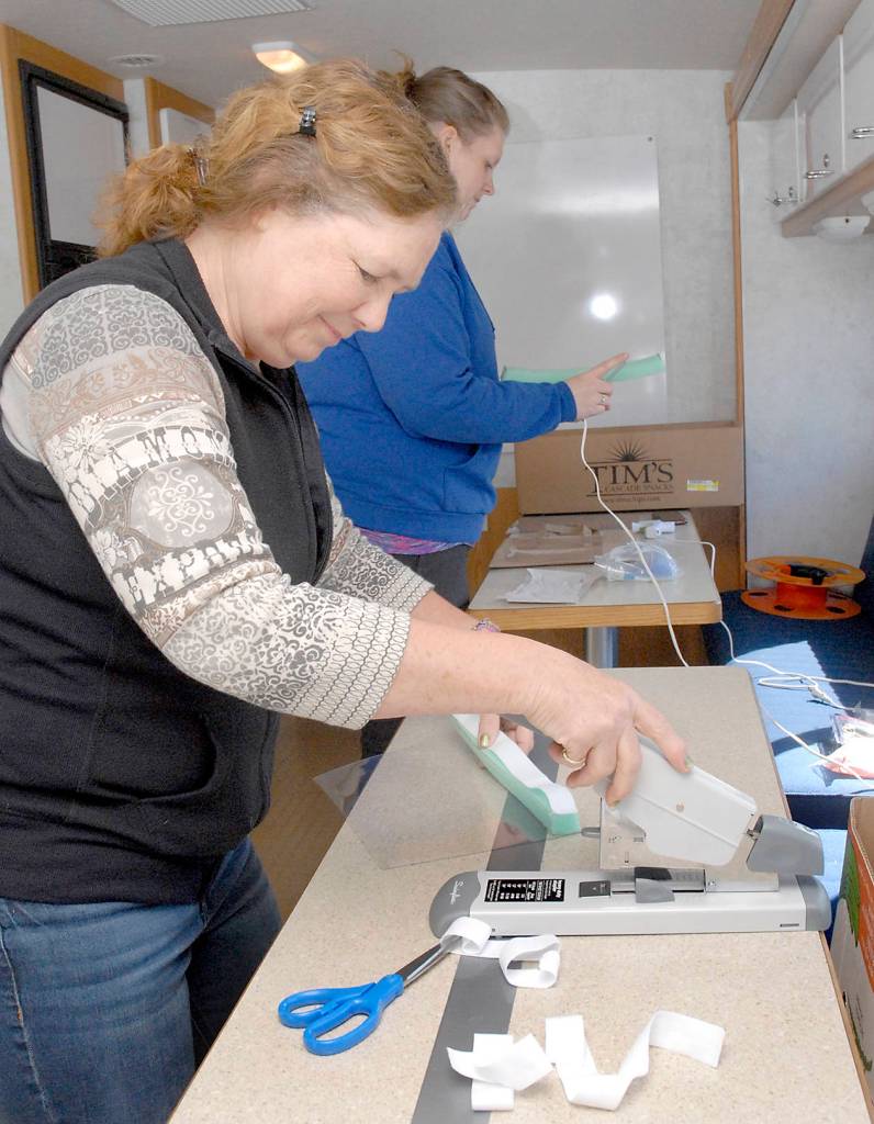 Volunteers Donna Fraser of Port Angeles, front, and Lori Shafer of Joyce fashion homemade face shields to be used by first responders when interacting with potential COVID-19 patients. The pair were working last week in the countys emergency management vehicle outside the Clallam County Courthouse in Port Angeles. Photo by Keith Thorpe/Olympic Peninsula News Group