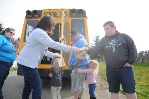 Helping hand out meals to Sequim youths on March 26 are, from left, bus driver Vienna Barron, teacher Gwen Rudzinski and Shirley Sheppard of Sodexo. The Sequim School District is distributing breakfast and lunch meals throughout the area each weekday. With parents Tony and Leslie Endicott (not pictured) looking on, Hadley, 4, Gracie, 3, and Logan, 14, receive their meals. Sequim Gazette photo by Michael Dashiell