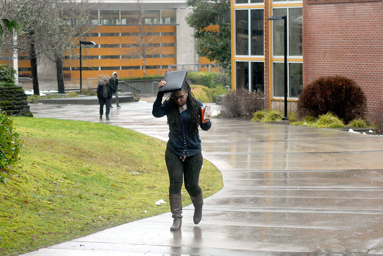 Nitasha Lewis, a manager with the Upward Bound program at Peninsula College, uses a paper valise to keep her head dry as she walks across the colleges Port Angeles campus on Feb. 6. The college is going to online classes for the entirety of the 2020 spring quarter. File photo by Keith Thorpe/Olympic Peninsula News Group