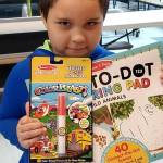 Seven-year-old Emmanuel Juanez shows some of the books he received from Dungeness Kids Co. The business matched each purchased activity pad and sticker book for the Sequim and Port Angeles Boys & Girls Clubs of the Olympic Peninsula during the 
COVID-19 
pandemic. Photo courtesy of the Boys & Girls Clubs of the Olympic Peninsula