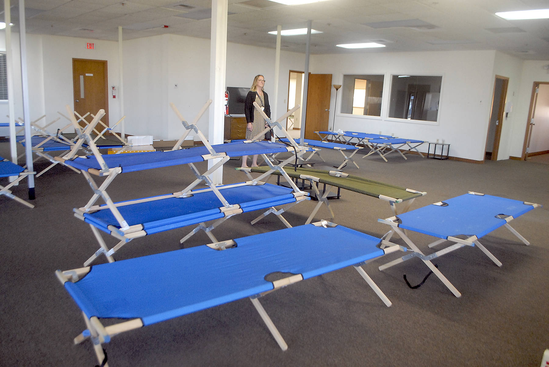 Jess Pankey, an environmental health specialist with Clallam County Heath and Human Services, looks over a room filled with cots last week at the Port of Port Angeles 1010 Building near William R. Fairchild International Airport as the building is converted to an isolation shelter for homeless individuals who might be infected with the novel coronavirus. Photo by Keith Thorpe/Olympic Peninsula News Group