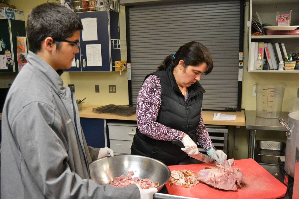 Andy and his mom Anita Benitez prep ham for split pea and ham soup during a recent night of soup prep. Anita is one of many Sequim School District staffers volunteering with the program. Sequim Gazette photo by Matthew Nash