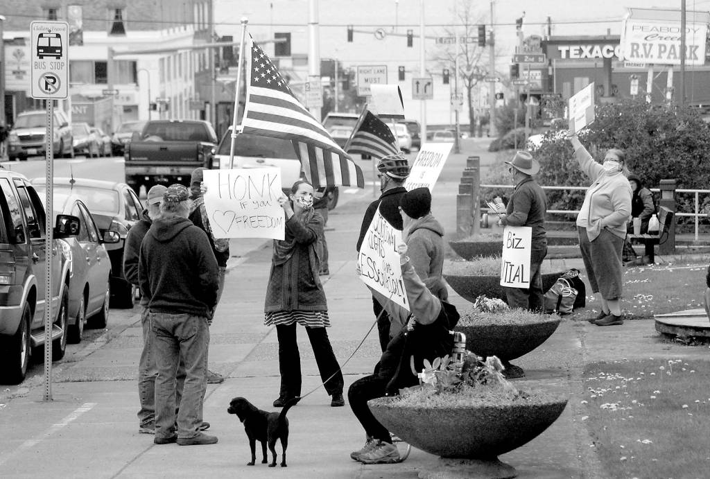 A group of about a dozen people against the states stay-at-home directives to combat spread of COVID-19 wave signs and flags at a gathering on Thursday, April 23, at Veterans Park in Port Angeles. Photo by Keith Thorpe/Olympic Peninsula News Group