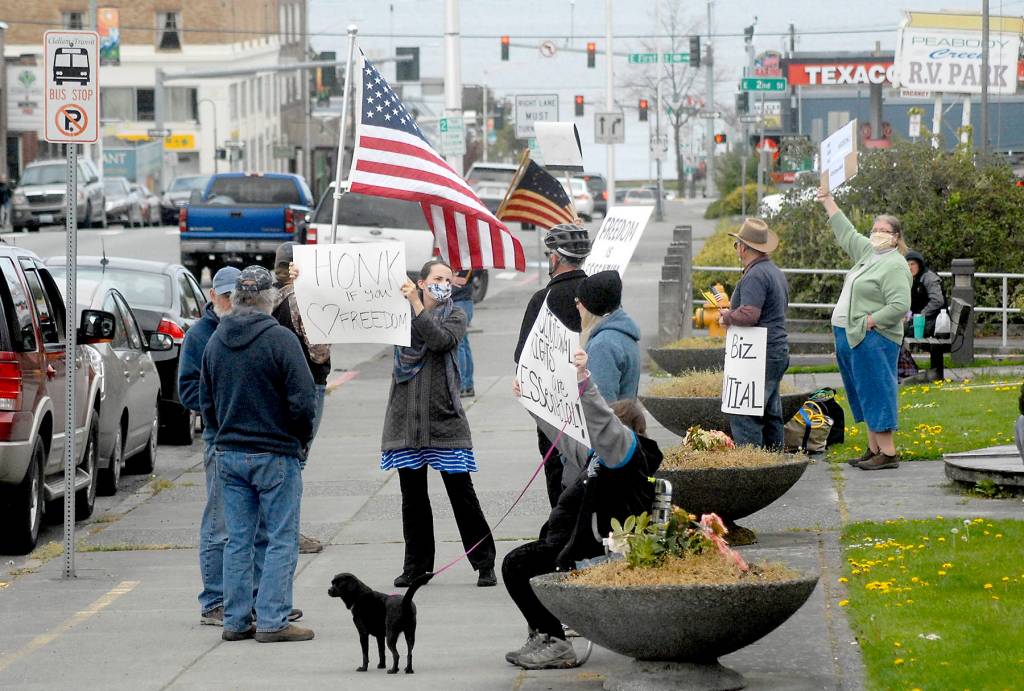A group of about a dozen people against the states stay-at-home directives to combat spread of COVID-19 wave signs and flags at a gathering on Thursday, April 23, at Veterans Park in Port Angeles. Photo by Keith Thorpe/Olympic Peninsula News Group