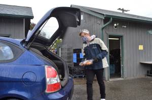 Logan Laxson loads a car with rolls on May 2 as part of a team of youths that volunteer at the Sequim Food Bank on Saturdays. That day would have been the second day of the Sequim Irrigation Festival, which Laxson serves on as a prince for the royalty court. Its rough not to have a festival, but it could be worse, he said. Ill get a festival in October. Sequim Gazette photo by Matthew Nash