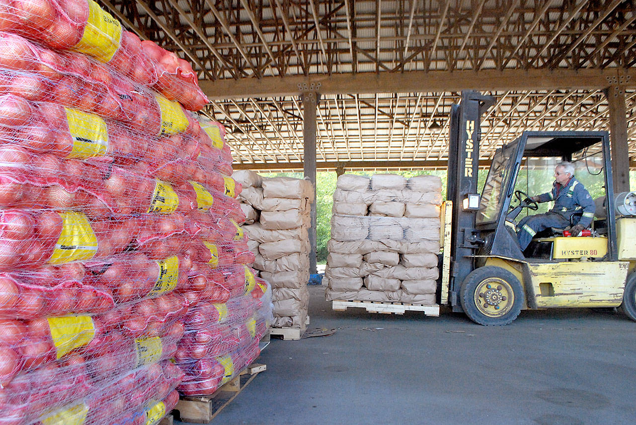 Dan Otterstetter, an employee of Hermann Brothers Logging & Construction Inc., uses a fork lift to unload potatoes and onions at the companys Port Angeles log yard Tuesday for storage before community distributions set for Saturday. Photo by Keith Thorpe/Olympic Peninsula News Group
