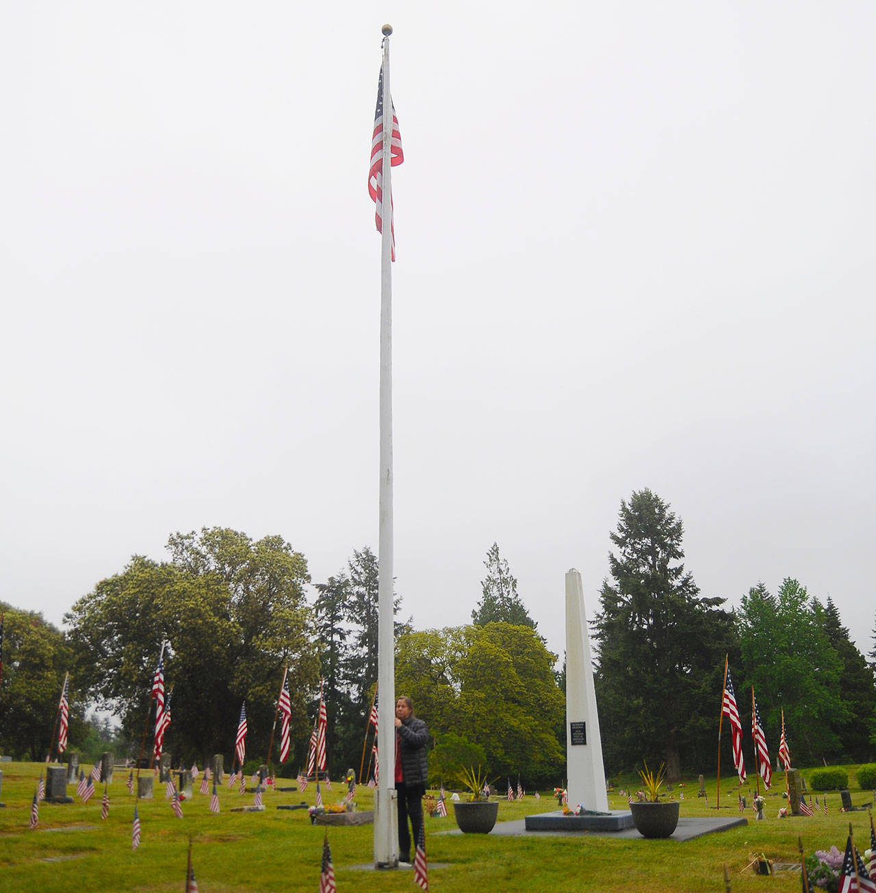 Deidre Magner, longtime groundskeeper for Sequim View Cemetery, raises the flag at the cemetery on Memorial Day just before noon. Flags at local cemeteries were lowered to half mast through mid-day Monday in recognition of the holiday. Local veterans groups cancelled Memorial Day ceremonies with a statewide ban on large gatherings in place. Sequim Gazette photos by Michael Dashiell