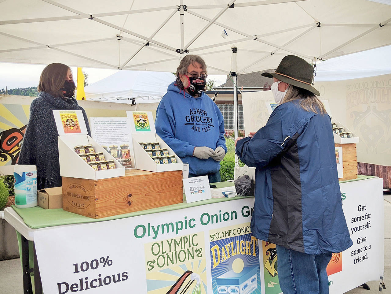 Vince Gipson with daughter Stephanie Parker of Olympic Onion Farm help a customer at the Sequim Farmers & Artisans Market. Photo by Emma Jane Garcia