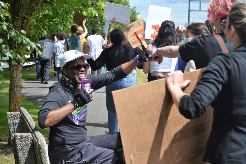 Deej Jones of Sequim fist bumps 
demonstrators as they march along Washington Street in support of the Black Lives Matter movement, and against police brutality and racism. Sequim Gazette photo by Matthew Nash