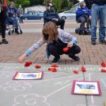Eleven-year-old Maisy French of Sequim places flowers down by pictures of black people victimized by police brutality on June 5 at the Sequim Civic Center. She participated in the vigil with her parents and brother with her mom Tammy saying they participated because they wanted to make sure something is done about the violence occurring in the nation.