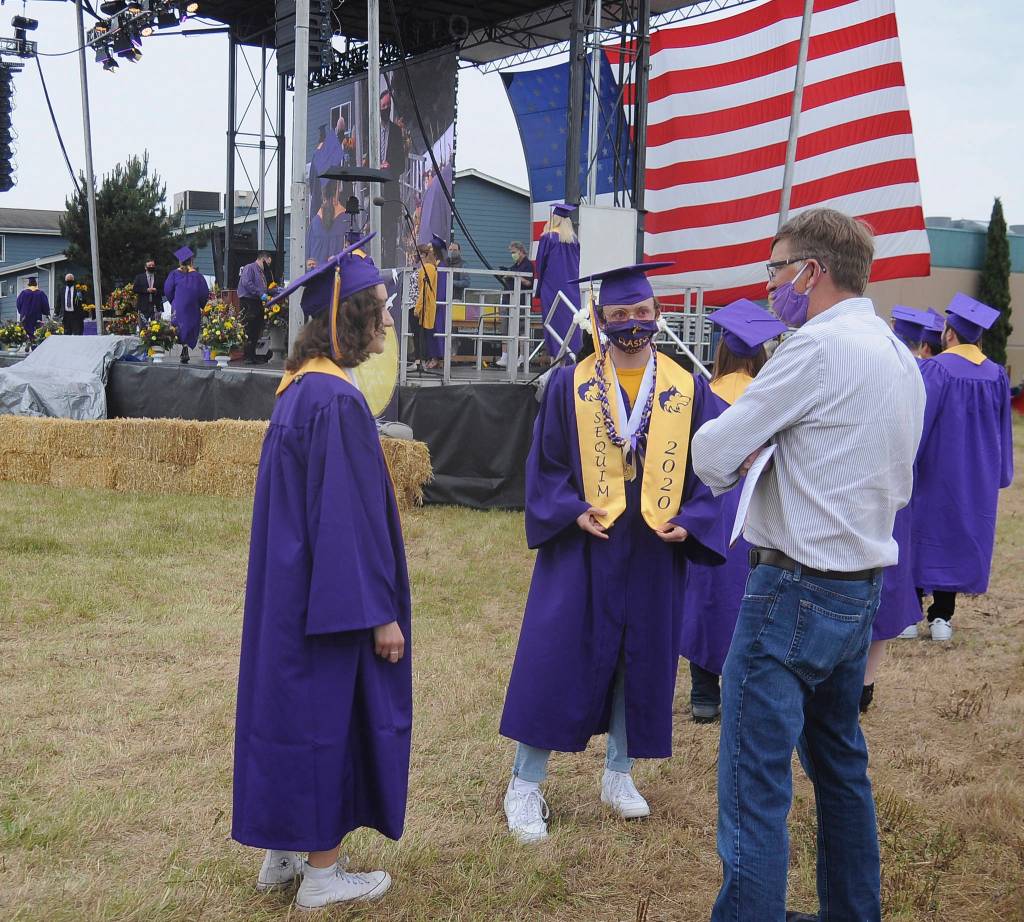 Sequim High School graduates-to-be (left) Wren Fierro Burdick and Kyle Desumma talk with teacher Michael Lippert at Fridays SHS commencement ceremony. Sequim Gazette photo by Michael Dashiell