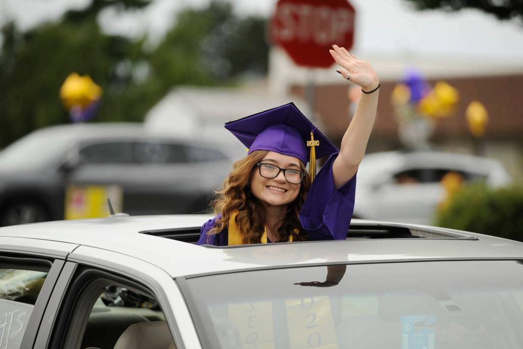 Above: Graduating senior Adam Awawda is all smiles as he receives his diploma and gets a flower from Sequim school superintendent Dr. Rob Clark at Fridays SHS commencement ceremony. Left: Sequim High graduates-to-be Morgan Cariou, right, and Lydia Stidham wave to well-wishers along Washington Street. Sequim Gazette photos by Michael Dashiell and Matthew Nash