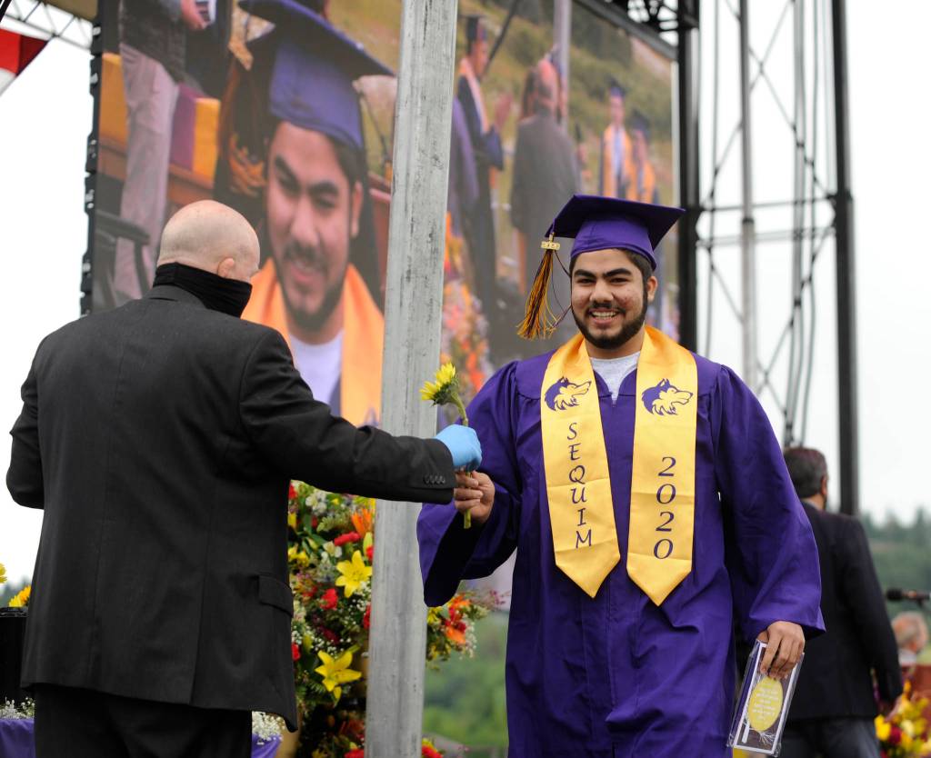 Graduating senior Adam Awawda is all smiles as he receives his diploma and gets a flower from Sequim school superintendent Dr. Rob Clark at Fridays SHS commencement ceremony. Sequim Gazette photo by Michael Dashiell