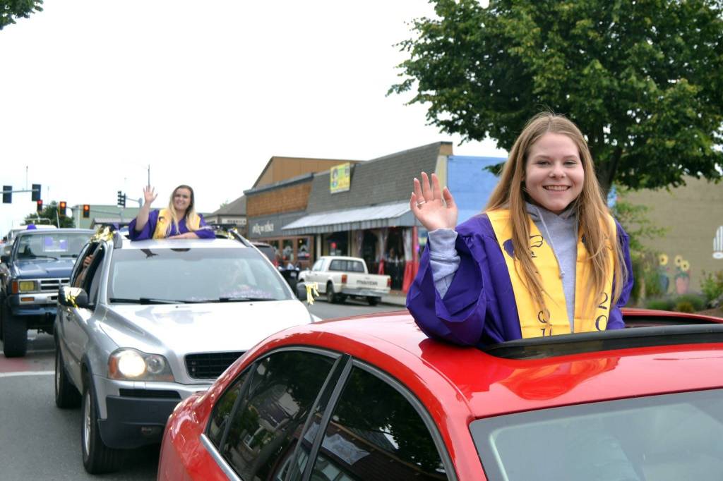 Sequim High graduates-to-be Morgan Cariou, right, and Lydia Stidham wave to well-wishers along Washington Street just prior to Sequim High Schools graduation ceremony on June 19. Sequim Gazette photo by Matthew Nash