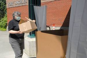 Mary Givins, a student librarian at the Port Angeles Public Library, takes part in a trial run to initiate curbside drop-off of returning books in the drive-in front of the library on June 16. The four North Olympic Library System libraries began curbside returns on June 17. Photo by Keith Thorpe/Olympic Peninsula News Group
