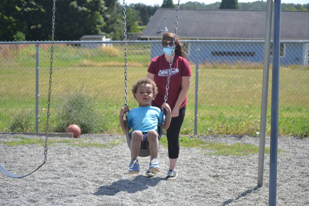 Sarah Schmedding pushes Harry Piper on the swings at Bibity Bobity last week. As some of the provisions at the center, parents must remain in the lobby, staff and childrens temperatures are taken, and social distancing is required between age groups. Sequim Gazette photo by Matthew Nash
