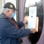 Tim Wheeler of Sequim, acting chairman of the non-partisan Voices for Health and Healing, attaches an envelope containing a letter on the front door of the building housing the Port Angeles office of U.S. Rep. Derek Kilmer on Thursday, July 23. The letter, signed by reportedly some 120 people, expressed disappointment in Kilmers progress in promoting universal health care, protection of Social Security and efforts to contain military spending, in particular the expansion of the U.S. Navys Growler aircraft training program at Naval Air Station Whidbey Island. Photo by Keith Thorpe/Olympic Peninsula News Group