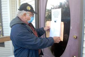 Tim Wheeler of Sequim, acting chairman of the non-partisan Voices for Health and Healing, attaches an envelope containing a letter on the front door of the building housing the Port Angeles office of U.S. Rep. Derek Kilmer on Thursday, July 23. The letter, signed by reportedly some 120 people, expressed disappointment in Kilmers progress in promoting universal health care, protection of Social Security and efforts to contain military spending, in particular the expansion of the U.S. Navys Growler aircraft training program at Naval Air Station Whidbey Island. Photo by Keith Thorpe/Olympic Peninsula News Group