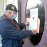Tim Wheeler of Sequim, acting chairman of the non-partisan Voices for Health and Healing, attaches an envelope containing a letter on the front door of the building housing the Port Angeles office of U.S. Rep. Derek Kilmer on Thursday, July 23. The letter, signed by reportedly some 120 people, expressed disappointment in Kilmers progress in promoting universal health care, protection of Social Security and efforts to contain military spending, in particular the expansion of the U.S. Navys Growler aircraft training program at Naval Air Station Whidbey Island. Photo by Keith Thorpe/Olympic Peninsula News Group