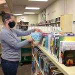 Annie Brooker sorts through books at the Sequim Library. Through libraries are closed to the public, NOLS staff are able to help readers find new books through a variety of services. Photo courtesy of North Olympic Library System