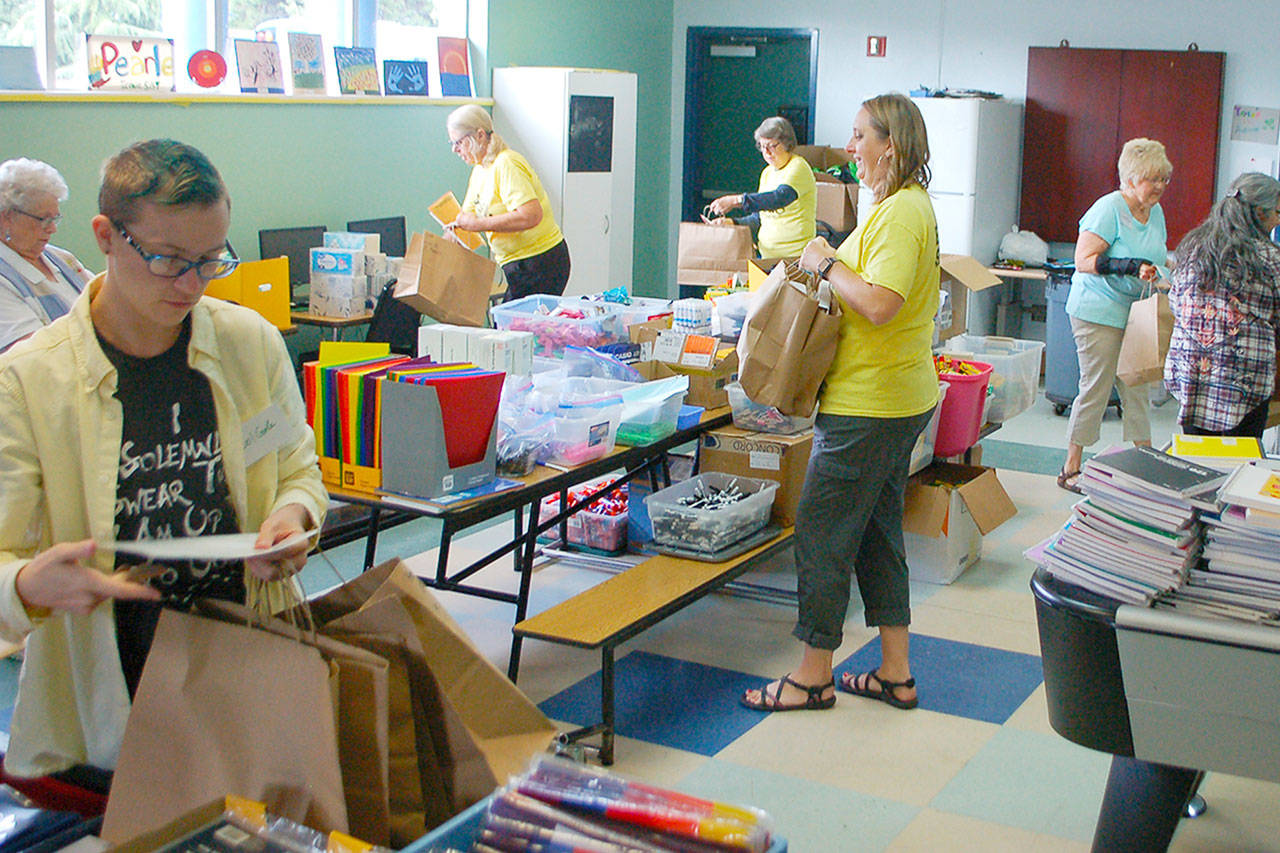 Janet Gray (third from right) and volunteers fill bags with school supplies for students at the 2019 Sequim Back To School Fair. This years fair is set for Aug. 29. With a number of health restrictions in place, organizers have changed the event to a drive through model. Sequim Gazette file photo by Conor Dowley