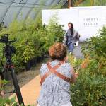 Videographer Silas Crews and photographer Cindy Roth capture Aurora Lagttuta walk the runway on Aug. 6 for Impact Fashions show in New Dungeness Nursery. The event will broadcast from Impact Fashions website on Sept. 4 and be part of a two-day summit on sustainable fashion. Sequim Gazette photo by Matthew Nash