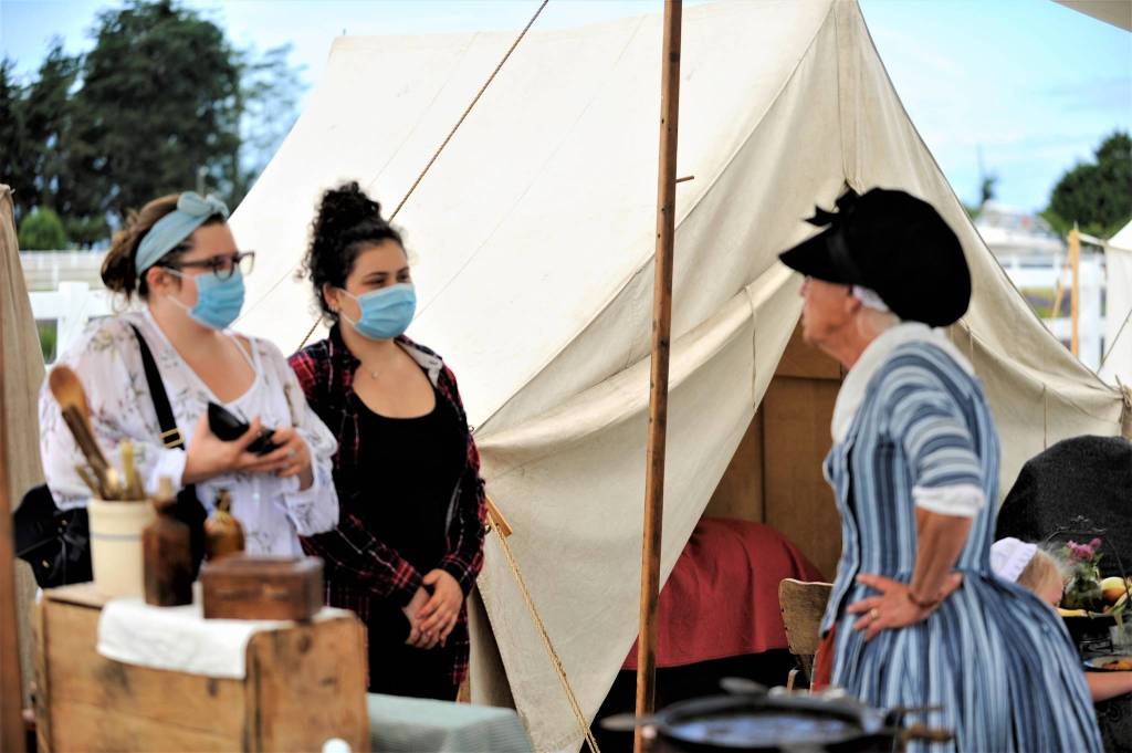 Sidnie Futerman and Amanda Babjko of Seattle chat with Linda Wickler during the adapted Northwest Colonial Festival on Aug. 8. Wickler was camping with three generations of her family as part of the Northwest Colonial Reenactors Association. Sequim Gazette photo by Matthew Nash