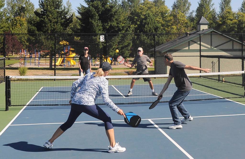 With doubles teammate Sue Haus (back, left) looking on, John Herbold lines up a shot as the pair take on Laurie McColl and Al Harris in pickleball play at Carrie Blake Community Park on Aug. 14. Sequim Gazette photo by Michael Dashiell