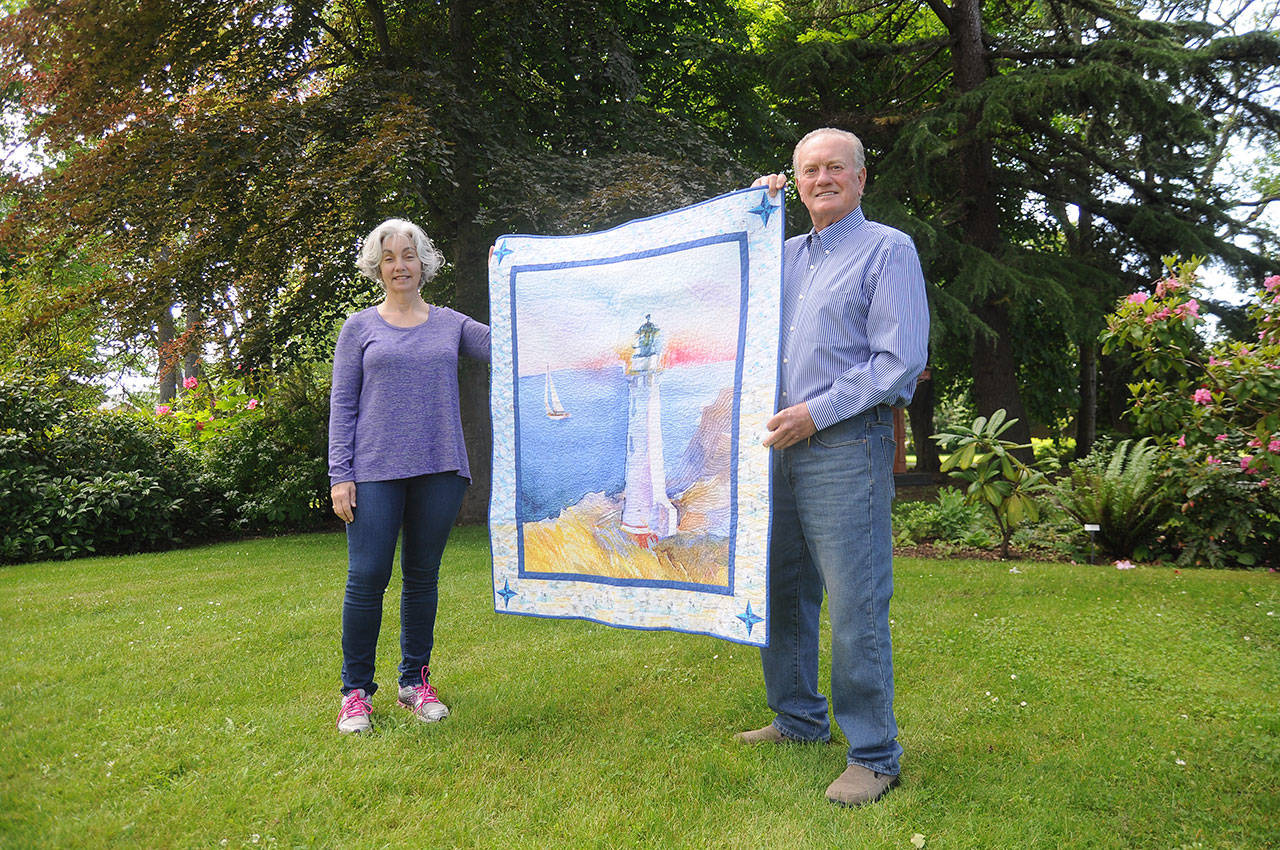 Quiltmaker Dory Miller of Crazy Horse Quilting and 2020 Sequim Bay Yacht Club commodore Jerry Fine display a quilt up for raffle, with proceeds going to Volunteer Hospice of Clallam County. Tickets are $5 each or six for $25. Organizers of the yacht clubs annual Reach and Row for Hospice recently announced the cancellation of the event, and are urging those looking to continue support of the effort to purchase raffle tickets or make a tax-deductible donation. Sequim Gazette photo by Michael Dashiell