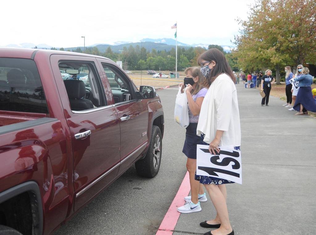 First-grade teachers Gwen Rudzinski, right, and Monique Brasher greet parents and students on Sept. 2, the first day of school for Sequim students, at Greywolf Elementary in Carlsborg. With studentsstarting the academic year learning remotely, teachers and staff handed out instructional materials at the campus. Sequim Gazette photo by Michael Dashiell