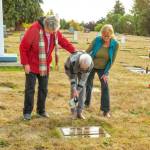Family members Meri Ninetman, Linda Barnes Butcher and Tricia Bekkevar help clean the headstone of World War I veteran Albert O.Wagner (1892-1976) at Sequim View Cemetery.