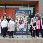 Gathered around the centennial quilt celebrating women achieving the right to vote in 1920, members of the Sunbonnet Sue Quilt Club and League of Women Voters of Clallam County say the raffle on Oct. 8 was the unofficial end to a yearlong celebration despite many events being canceled due to the pandemic. Sequim Gazette photo by Matthew Nash