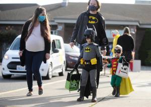 The Dynamic Duo of Batman and Robin (Truman, 5, and Archer, 2), accompanied by parents Luke and Aubrey Leishman of Sequim, enjoy some trick-or-treating at the Sequim High Schools Halloween event, modified this year for drive-thru and walk-thru guests. Sequim Gazette photos by Michael Dashiell