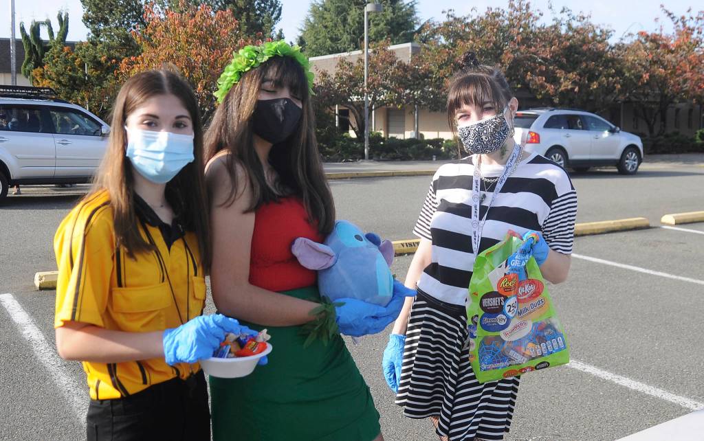 From left, Sequim High School students Alliyah Weber, Christina Caples and Delaney Nucci hand out candy at SHSs drive-thru Halloween event on Oct. 31. Sequim Gazette photo by Michael Dashiell