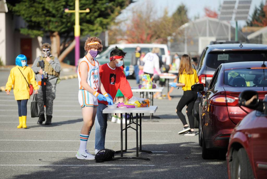 From left, Sequim High School students welcome guests at SHSs drive-thru Halloween event on Oct. 31. Jack Van De Wege, center, took top student costume honors for his Jackie Moon basketball costume. Sequim Gazette photo by Michael Dashiell