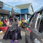 Kayleen McDonald of the Sequim unit of the Boys & Girls Clubs of the Olympic Peninsuila delivers bagged lunches to a waiting car as unit director Tessa Jackson looks on at left during a drive-thru Halloween in front of the organizations Sequim facility on Oct. 31. Besides lunch bags, trick-or-treaters were offered hats, treats and coloring books. Photo by Keith Thorpe/Olympic Peninsula News Group
