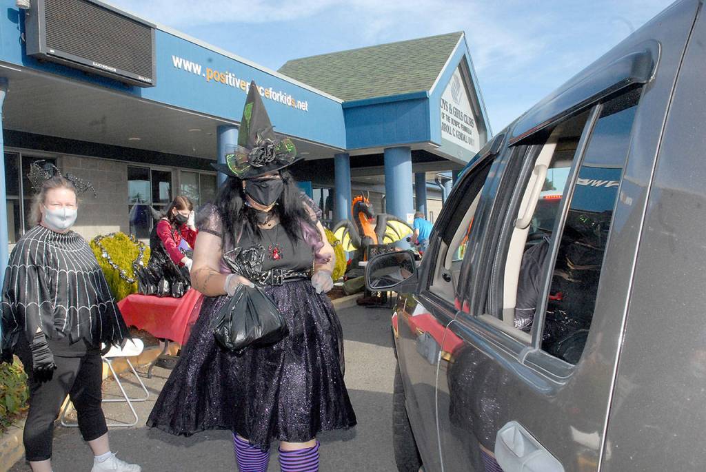 Kayleen McDonald of the Sequim unit of the Boys & Girls Clubs of the Olympic Peninsuila delivers bagged lunches to a waiting car as unit director Tessa Jackson looks on at left during a drive-thru Halloween in front of the organizations Sequim facility on Oct. 31. Besides lunch bags, trick-or-treaters were offered hats, treats and coloring books. Photo by Keith Thorpe/Olympic Peninsula News Group