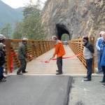 Lisa Turecek, facilities manager for Olympic National Park, and Rich James, former Clallam County Transportation Program Manager, wield ceremonial scissors to cut a ribbon to dedicate a reworked and refurbished Spruce Railroad Trail on the north shore of Lake Crescent on Thursday. (Keith Thorpe/Peninsula Daily News)