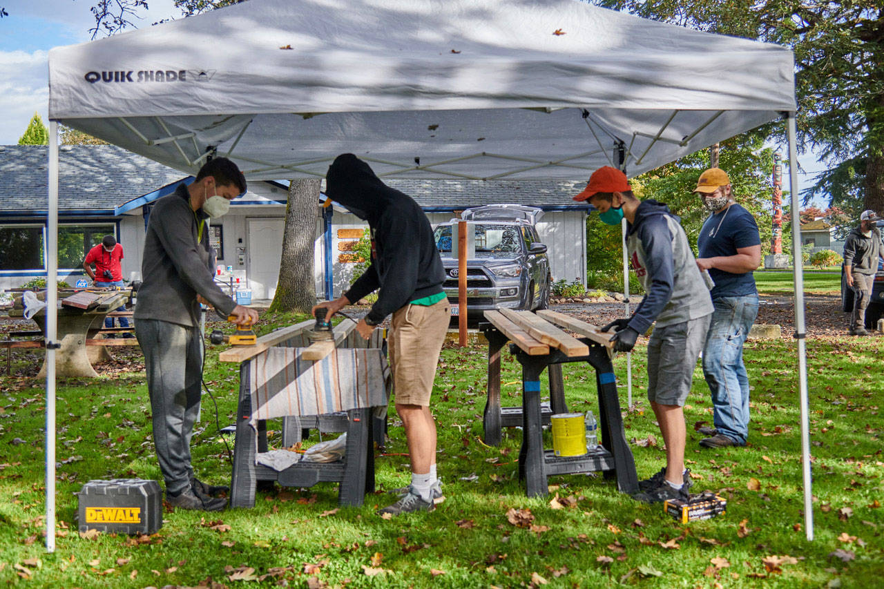 Above: Scouts and other volunteers help complete refurbishing of six picnic tables at Pioneer Memorial Park, part of Calem Ryne Klingers Eagle Scout project. At right: Klinger displays one of the refurbished picnic tables at Pioneer Memorial Park.Photos courtesy of Sequim Prairie Garden Club